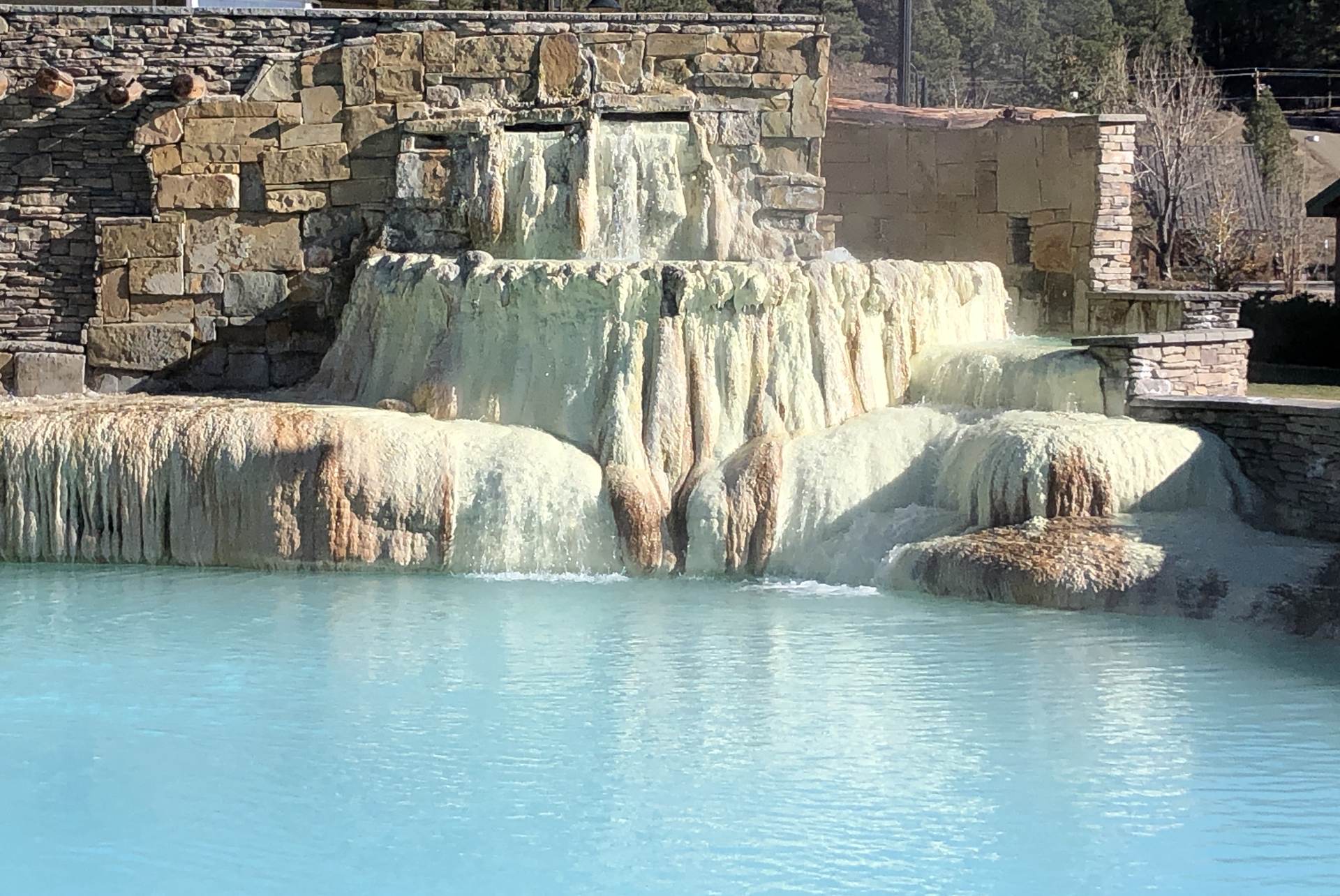 Mineral-stained terraces spilling into a turquoise hot springs pool at Pagosa Hot Springs