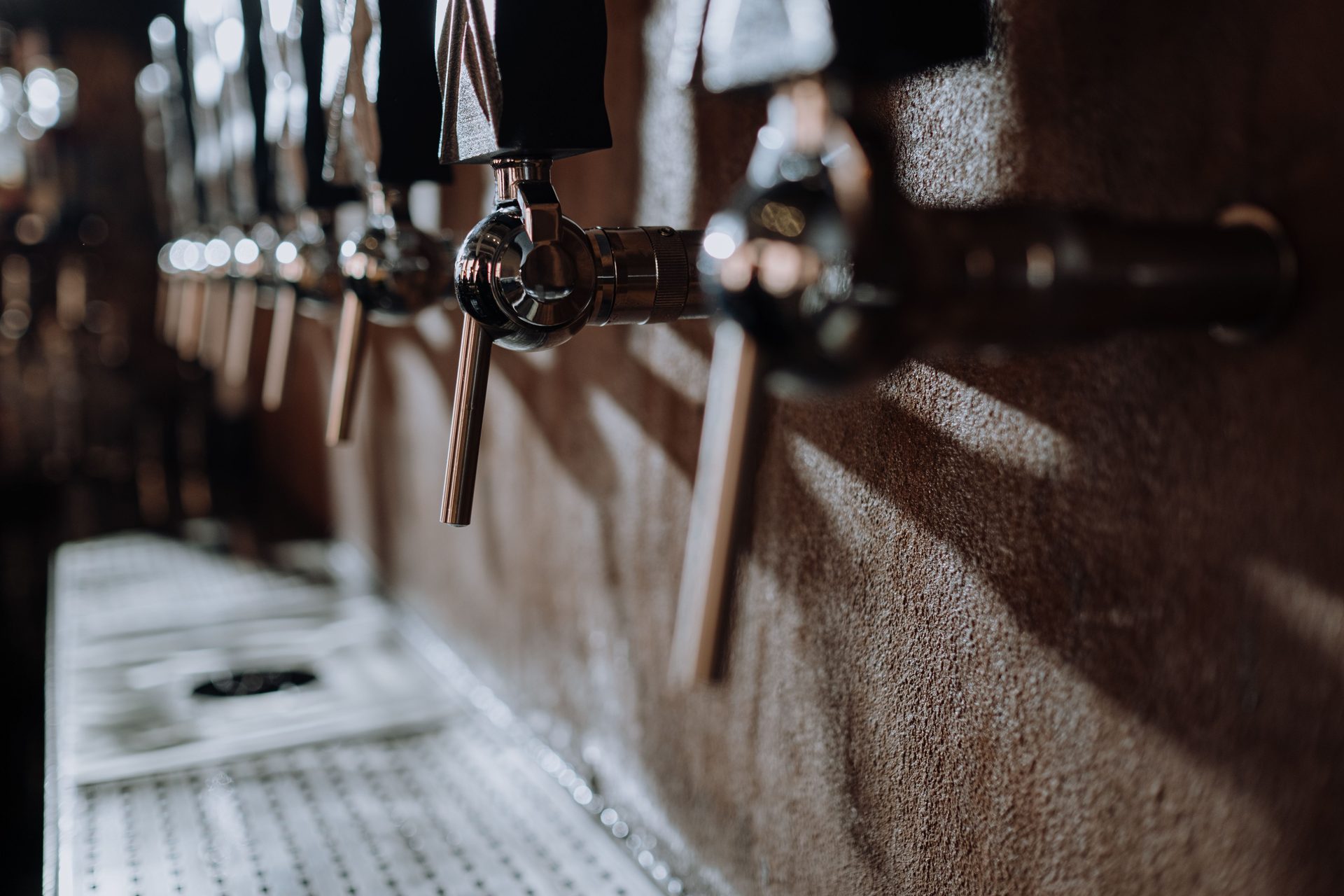 Row of beer tap handles along a bar in dim light