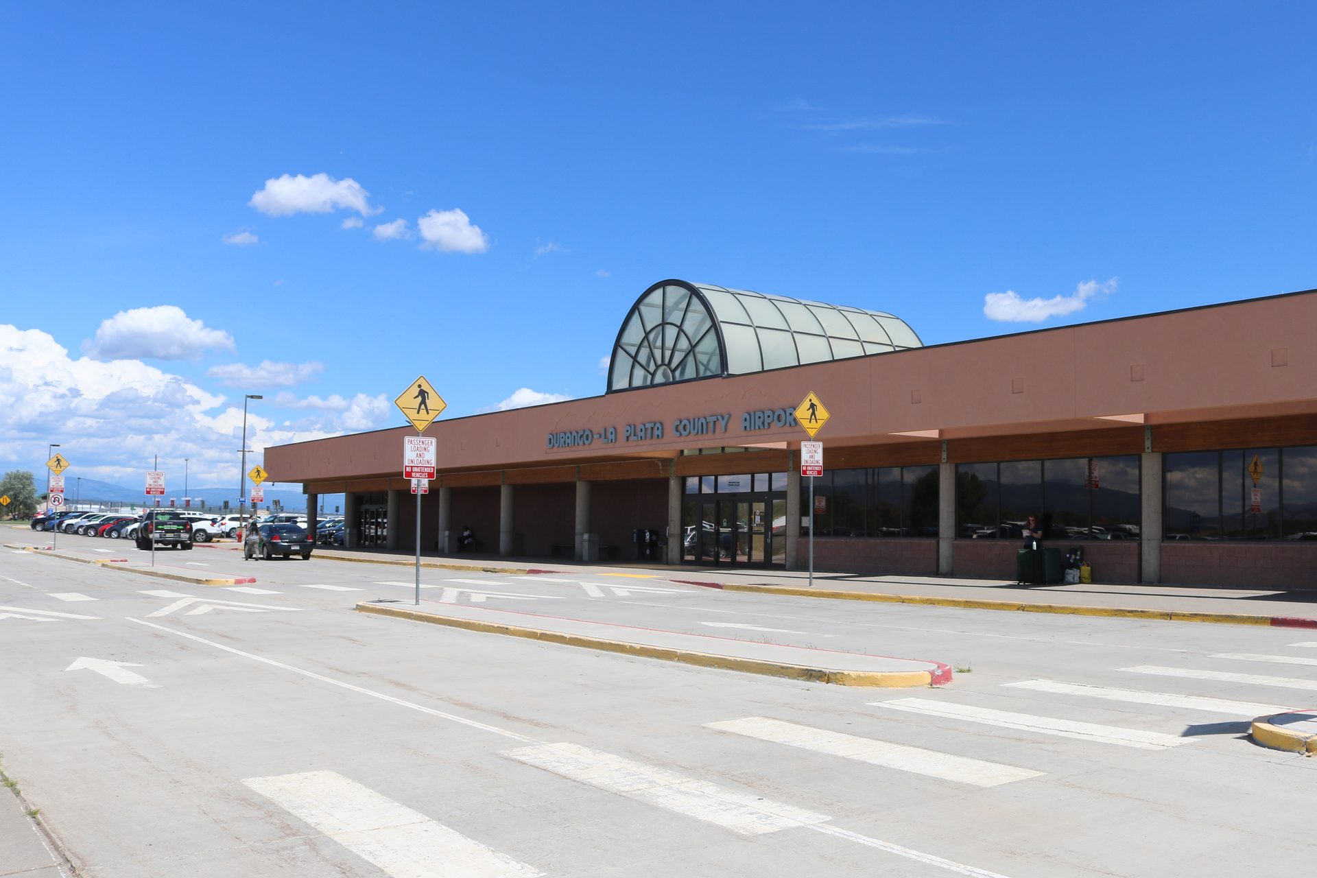 Terminal building of Durango-La Plata County Airport under a blue sky, seen from the curb and parking apron
