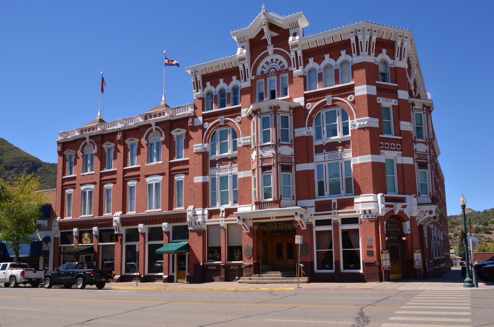 Red-brick Strater Hotel on Main Avenue in downtown Durango, its white-trimmed Victorian facade under a blue sky