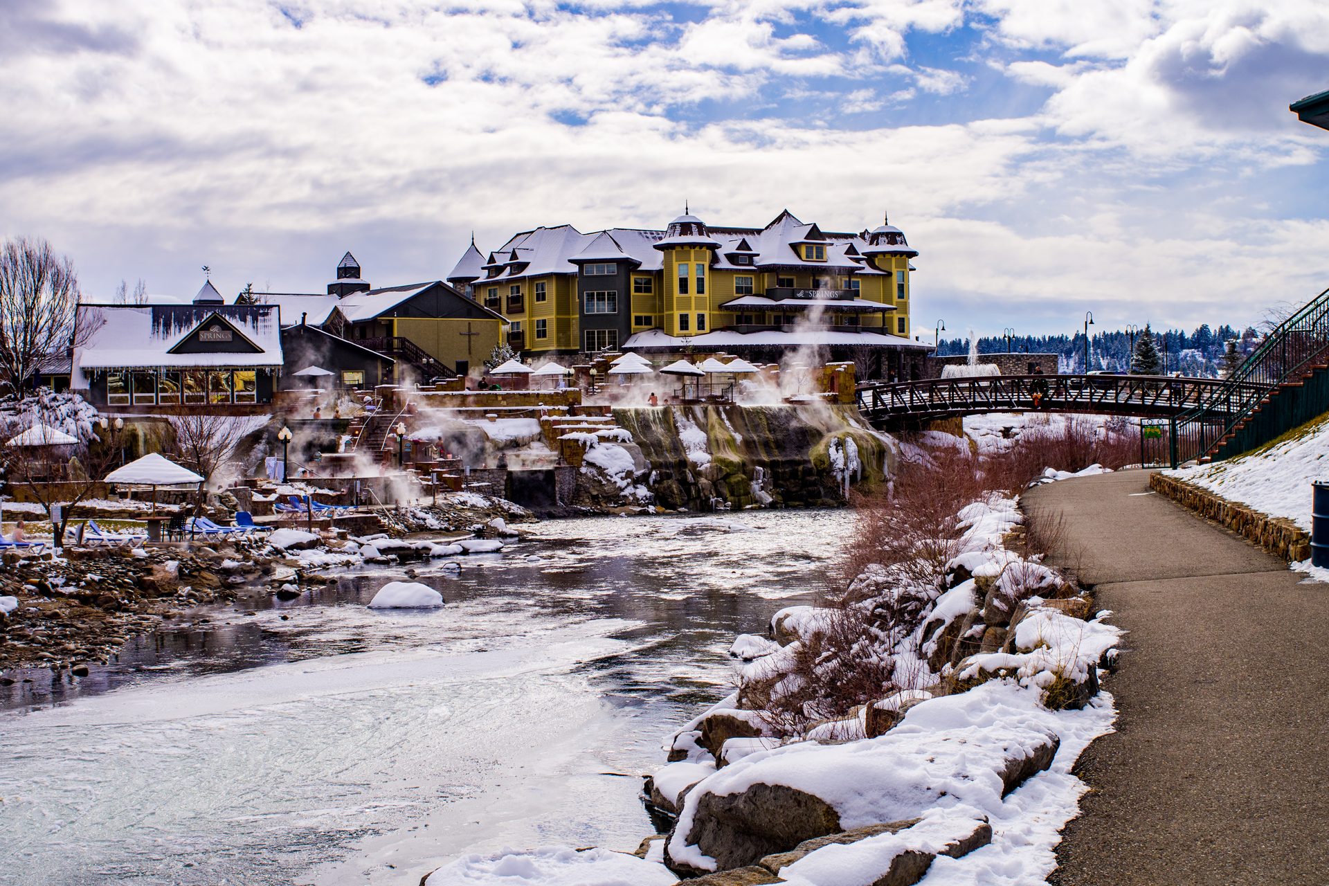 Steaming hot springs and a snow-dusted riverwalk below the resort buildings in Pagosa Springs