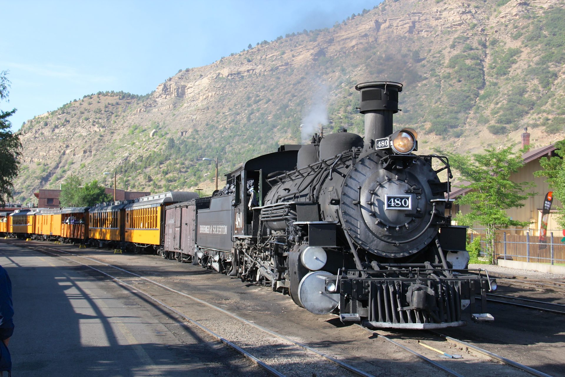 Durango & Silverton Narrow Gauge Railroad steam locomotive No. 480 pulling yellow passenger cars at the Durango depot