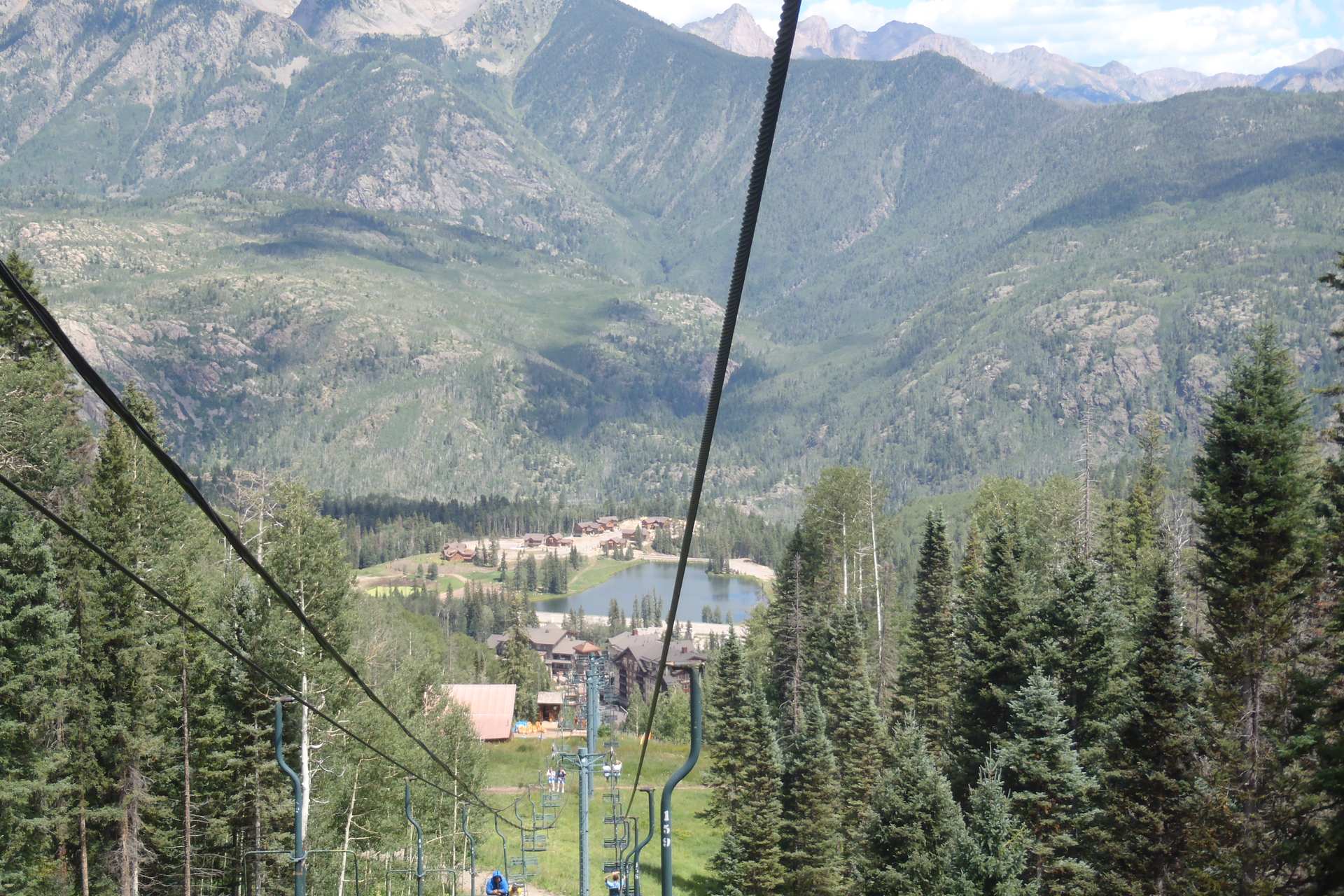 Purgatory base village with its pond and lodges, seen from the chairlift line looking down toward the San Juan Mountains