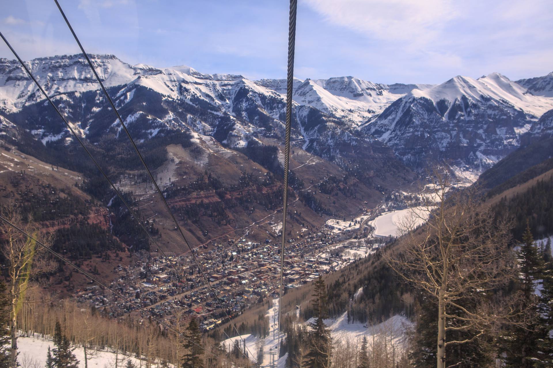 Chairlift cables above Telluride ski area looking down on the town and the snowy San Juan Mountains