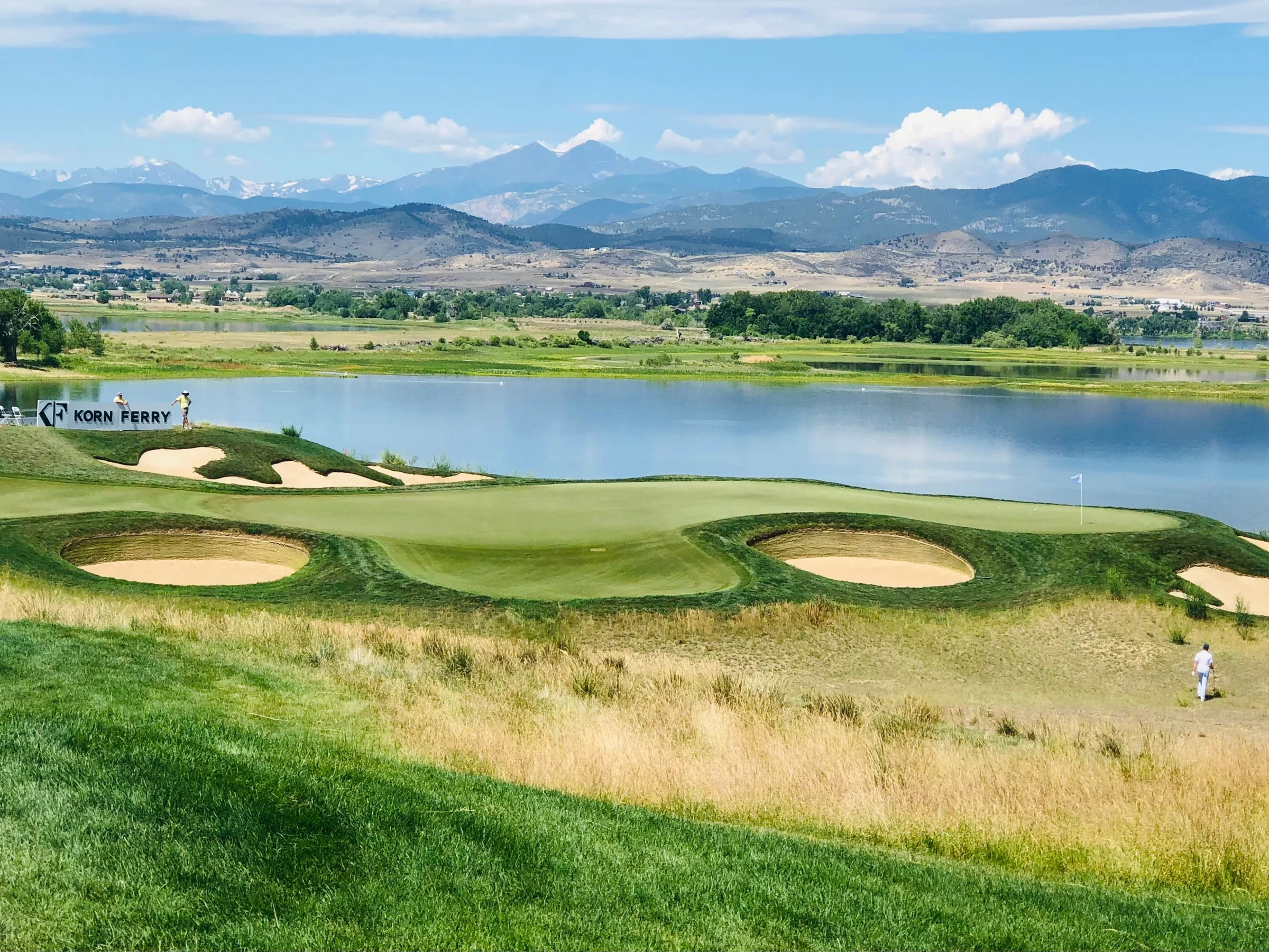 A golf green beside a lake with mountains in the distance